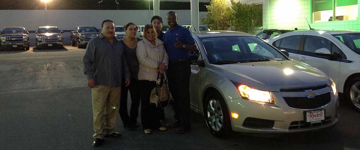 A family posed in front of their new car