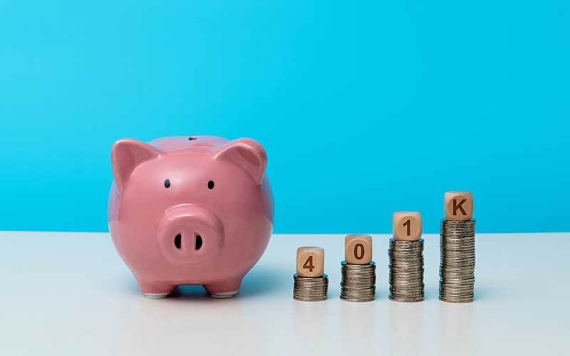 A piggy bank with stacks of coins with small cubes spelling out 401K