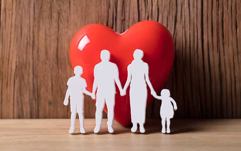 A heart with a paper cutout of a family in front